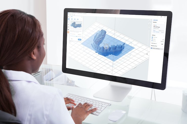 Rear view of female dentist examining jaw Xray on computer in clinic - Formlabs Dental