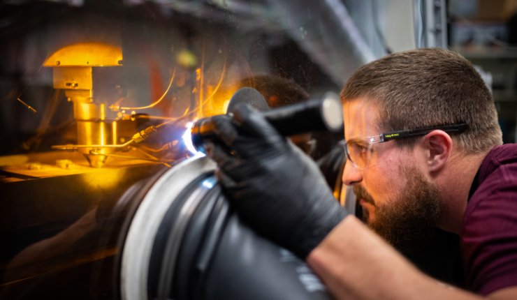 Sandia National Laboratories technologist Levi Van Bastian works to print material on the Laser Engineered Net Shaping machine, which allows scientists to 3D print new superalloys - Sandia...